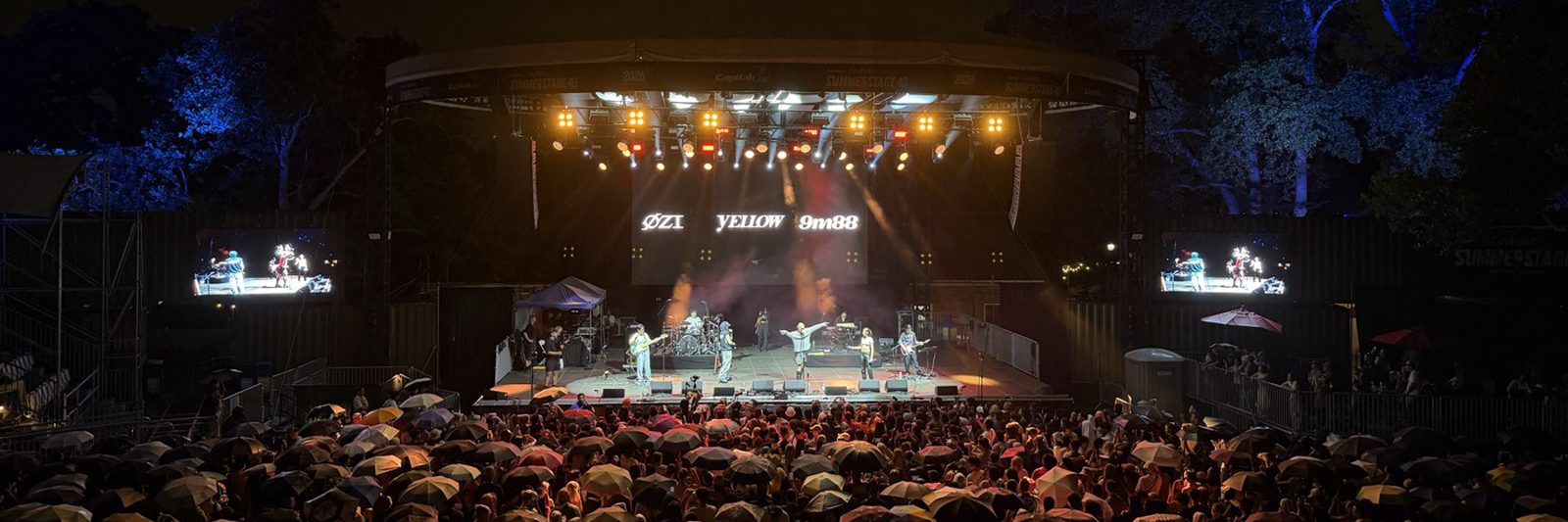 Taiwanese Waves at SummerStage, Central Park: the stage lit at night with the crowd under umbrellas.